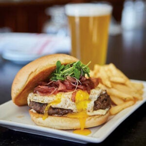 A cheeseburger and fries served with a beer