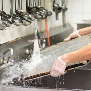 Worker washing a pan under a sink