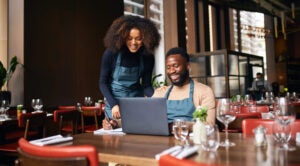 Woman and man working at restaurant with laptop