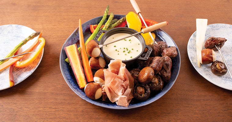 Holiday fondue plate featuring steak, cheese, pickled vegetables and pretzel bites