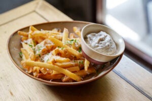 Bowl of fries next to lemon pepper parm dip