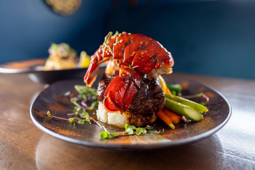 Surf and turf dish with a lobster tail on a beef tenderloin  served on plate