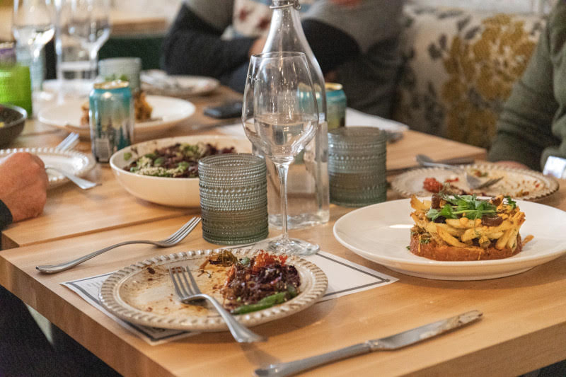 Les clients partagent des assiettes de frites gastronomiques, des salades et des boissons à une table de restaurant.